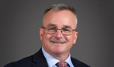 Headshot of Mike Adams in front of a black background